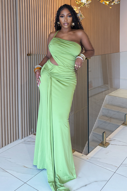 Woman in a green evening gown standing indoors with a neutral background