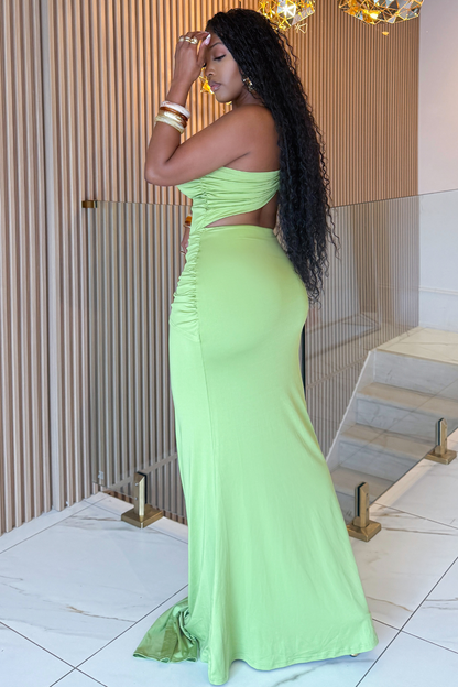 Woman in a green evening gown standing indoors with decorative elements in the background